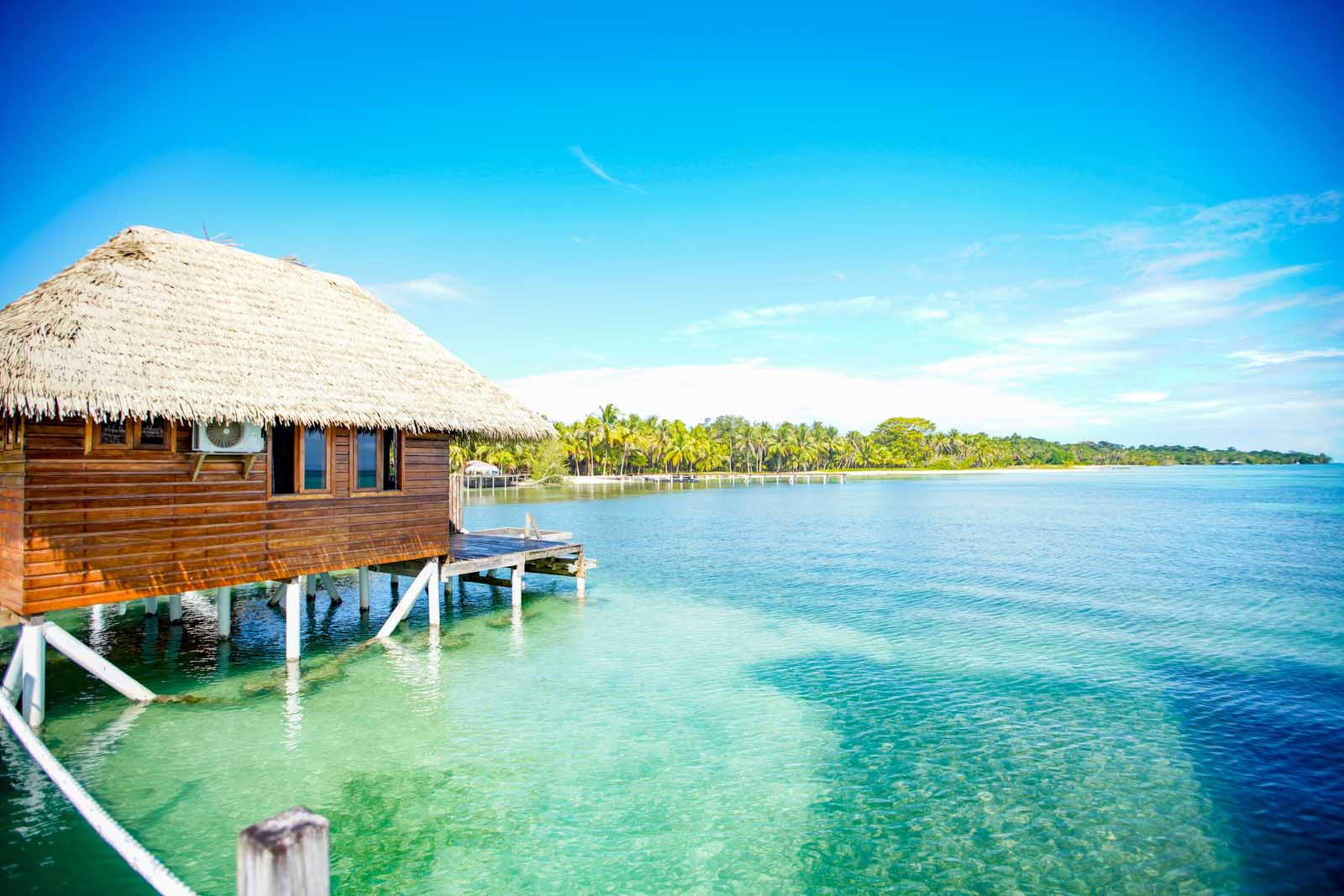 Rustic thatched-roof overwater bungalow at Azul Paradise, Bocas Town, floating above pristine beach waters