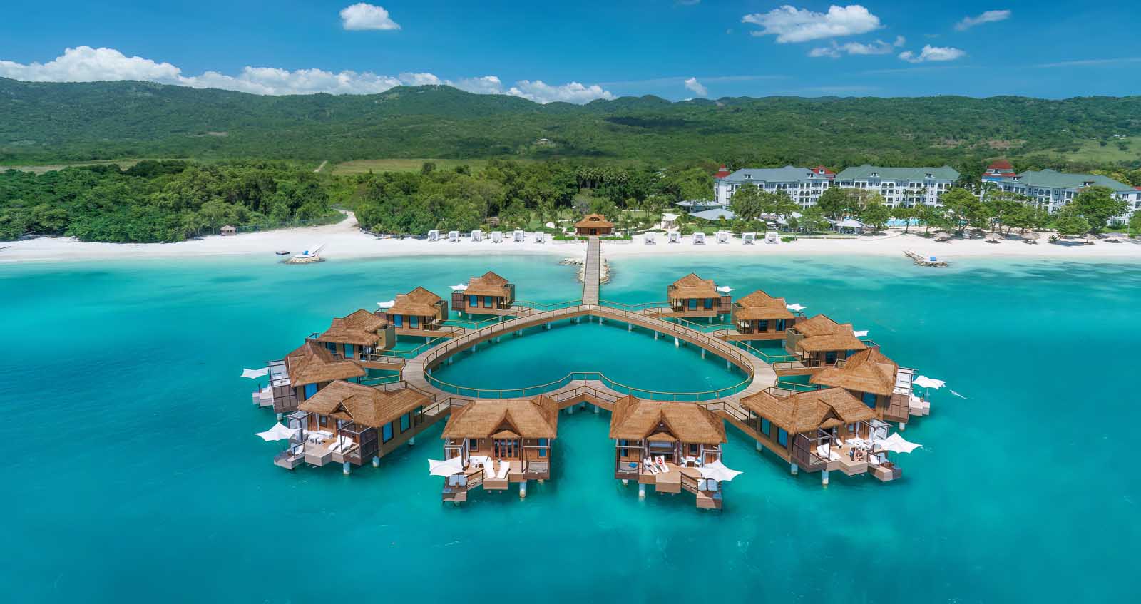 Heart-shaped overwater bungalow cluster at Sandals South Coast, Jamaica with glass floor panels and floating hammock