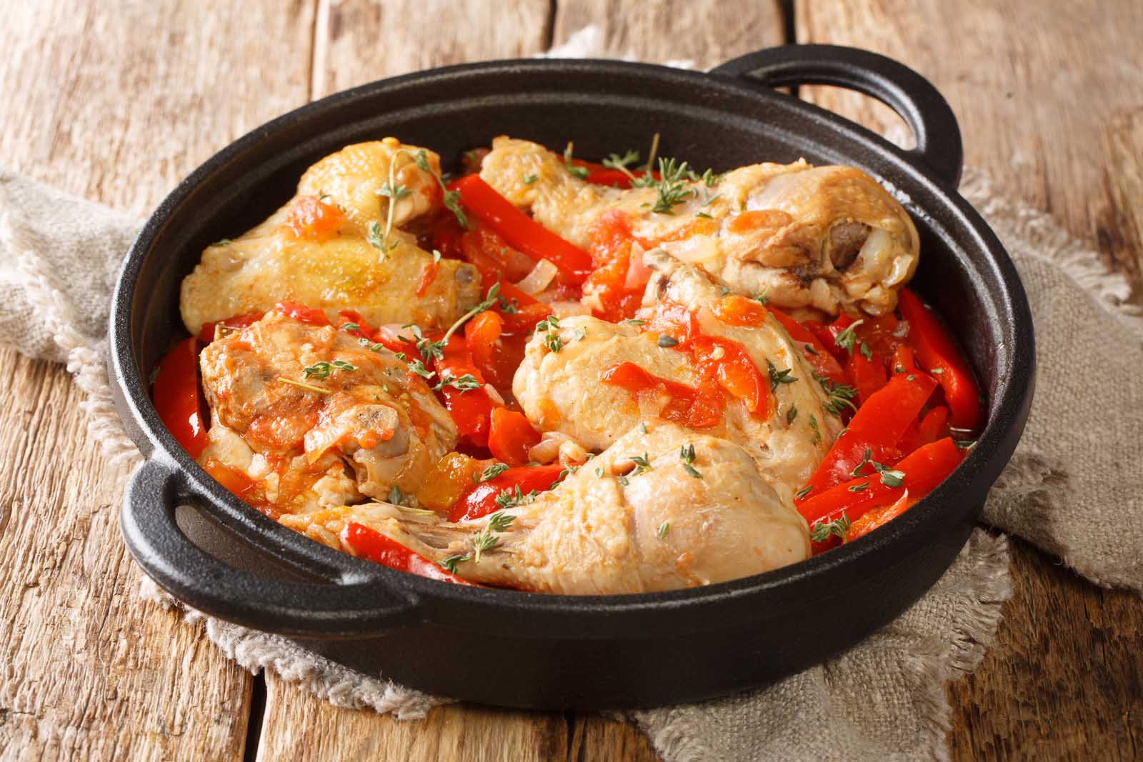 A vibrant dish of Poulet Basquaise, a French chicken stew with sweet peppers and Espelette chili.