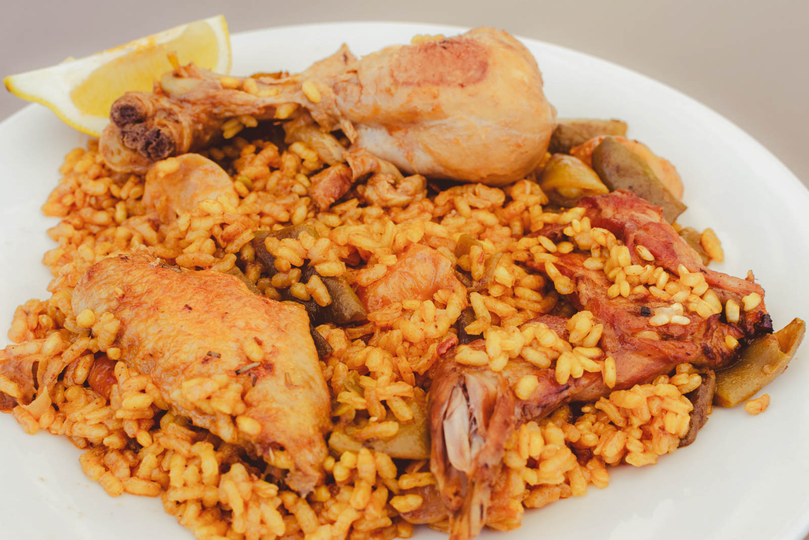 A scoop of Arroz Con Pollo on a plate, showing yellow rice mixed with tender pieces of chicken and red peppers.