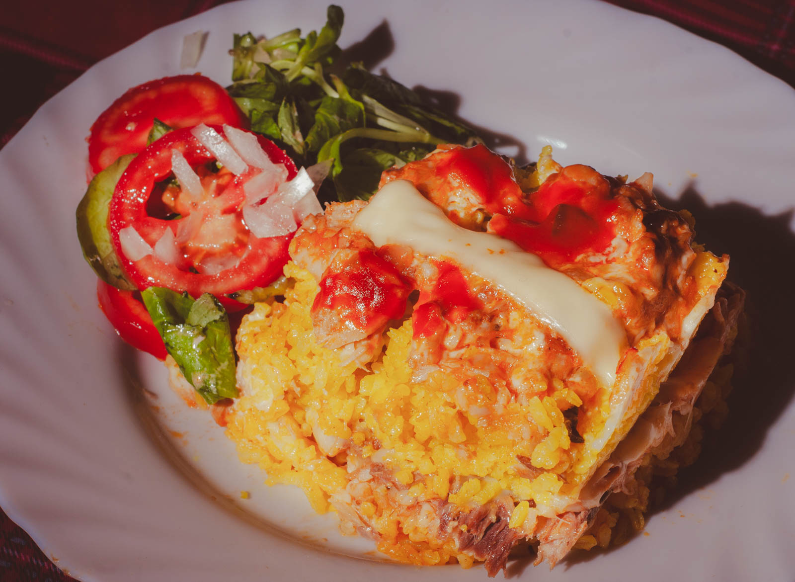 A square slice of Arroz Imperial on a spatula, showing the layers of yellow rice, shredded chicken, and melted cheese on top.