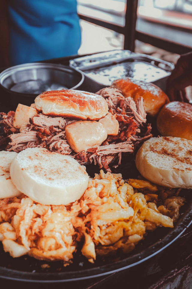 A Medianoche sandwich on a soft, sweet, golden egg-based bread, showing the classic fillings inside.