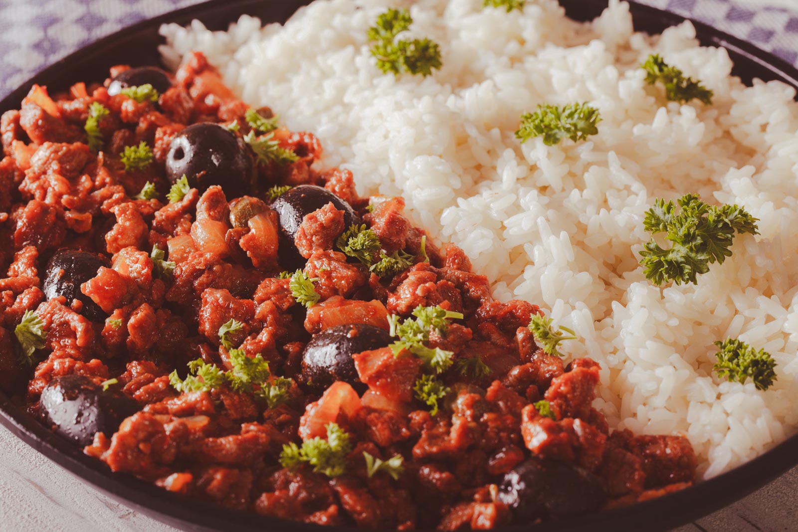 A bowl of Picadillo a la Habanera, a Cuban ground beef dish with green olives and potatoes in a savoury tomato sauce