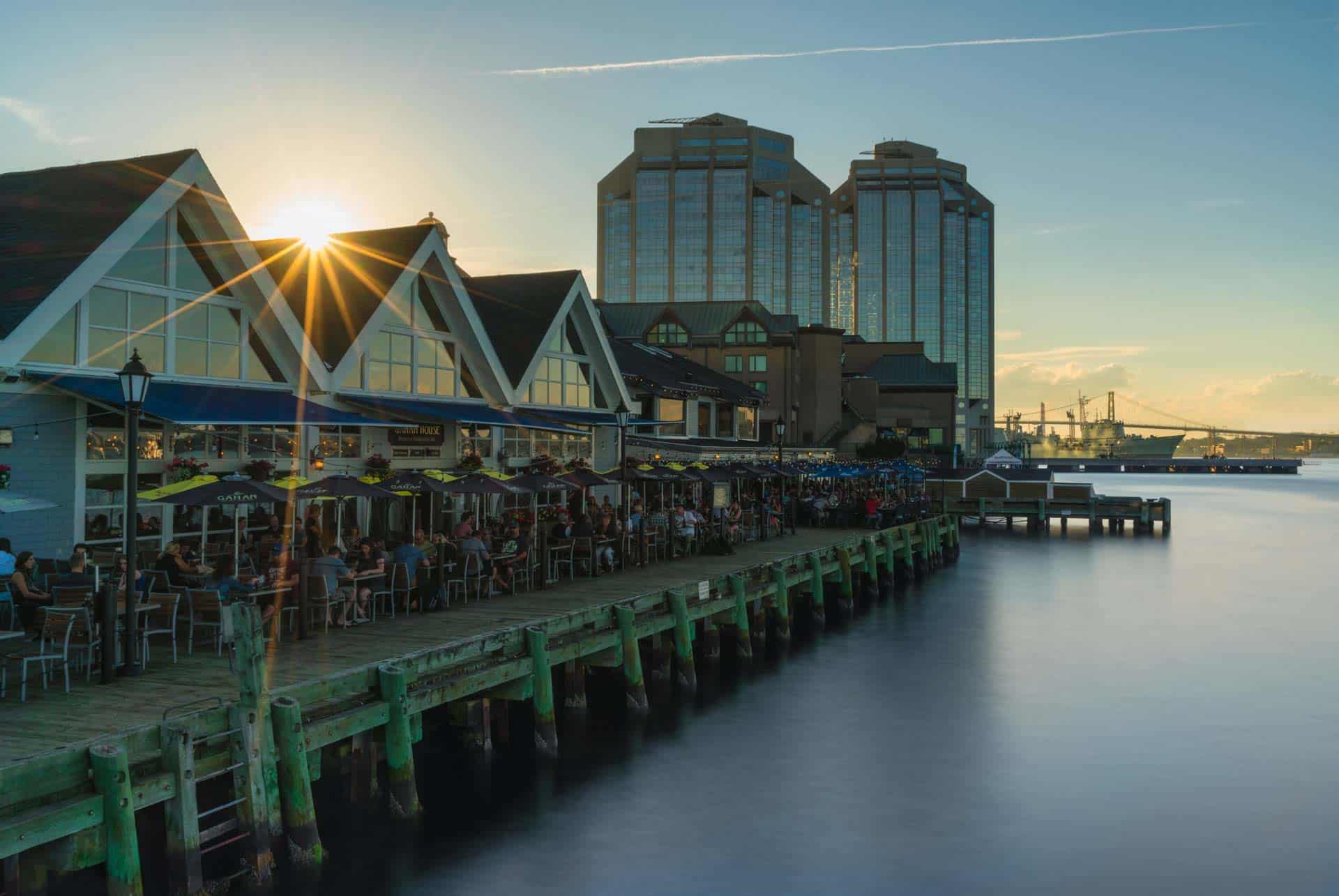 People strolling along the vibrant Halifax waterfront boardwalk on a sunny day.