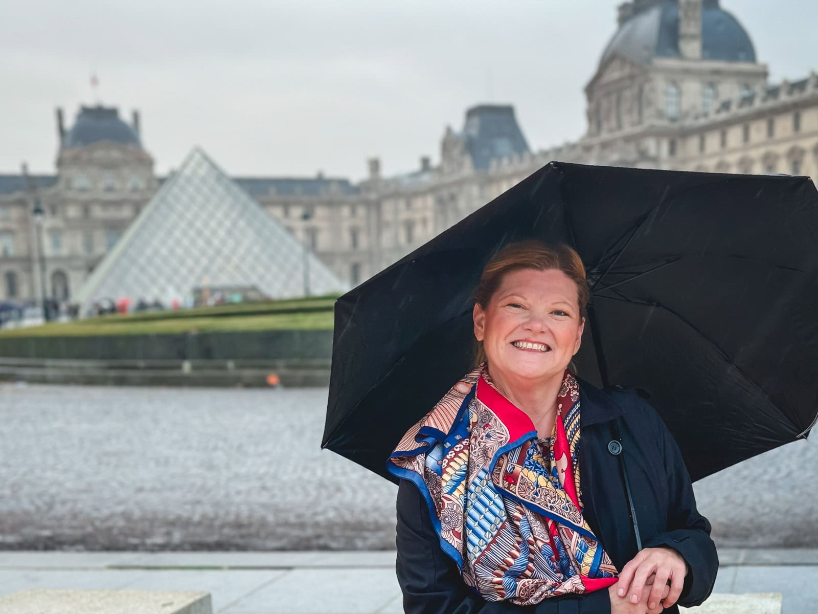 eb from The Planet D standing in front of the iconic glass pyramid at the entrance to the Louvre Museum.