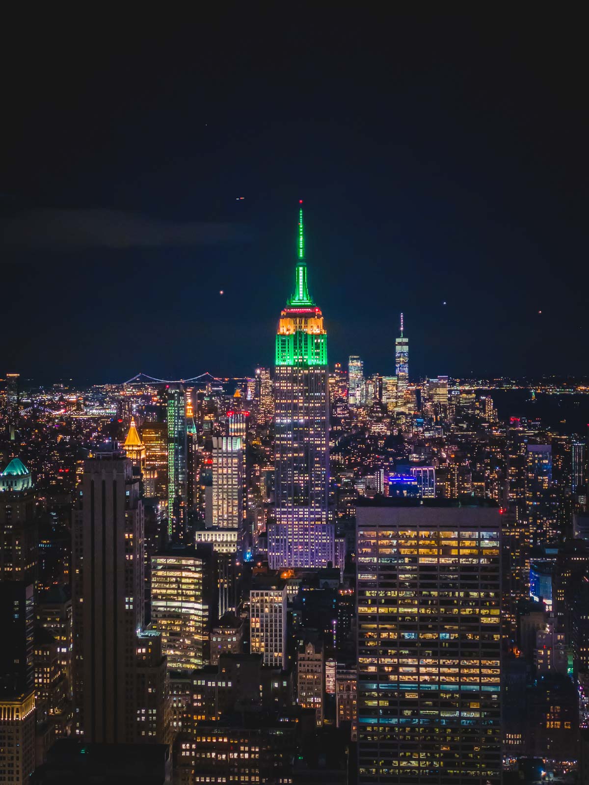 The top of the Empire State Building lit up with festive red and green lights for the Christmas season.