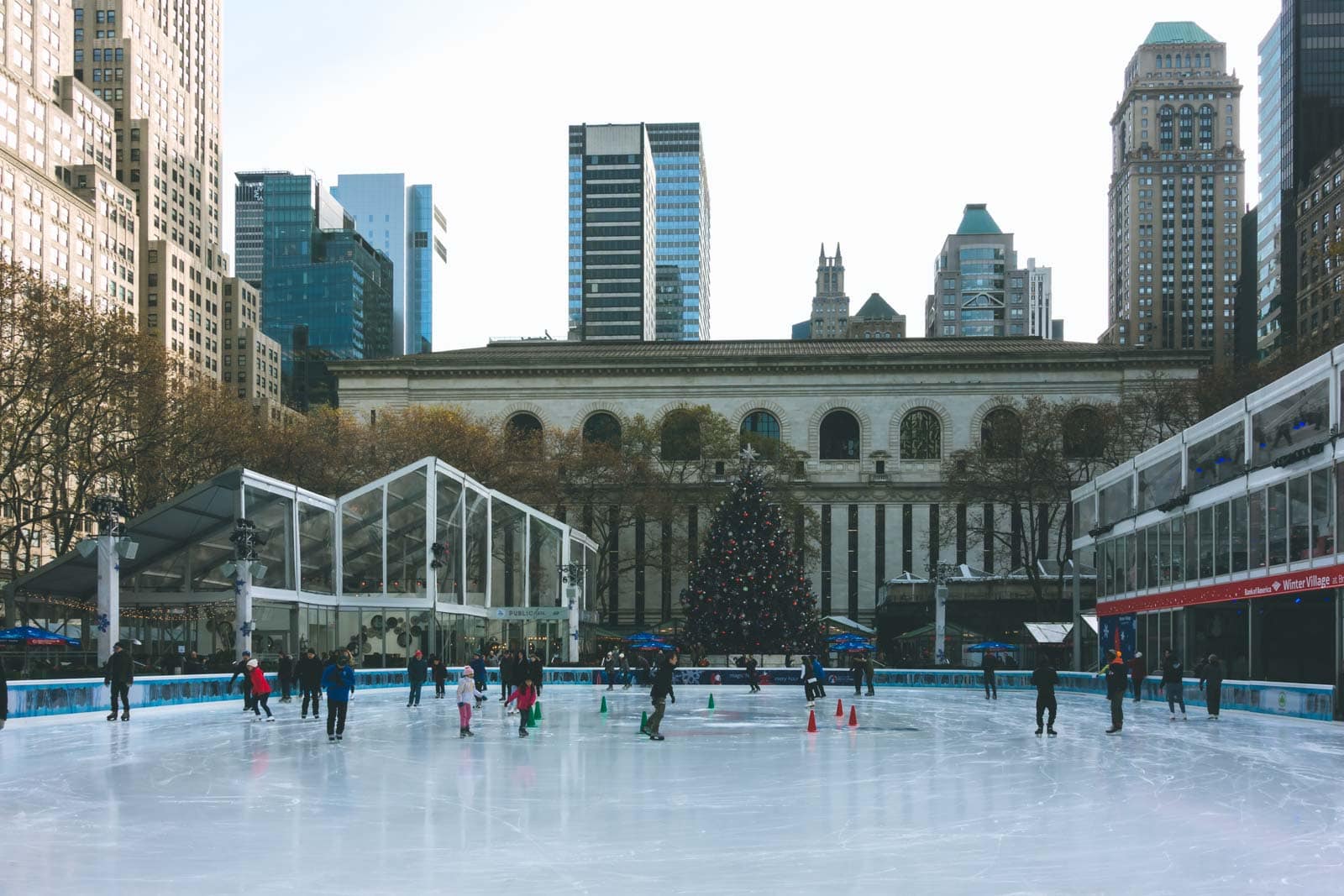 People ice skating at Bryant Park with the iconic Christmas Market in the background.