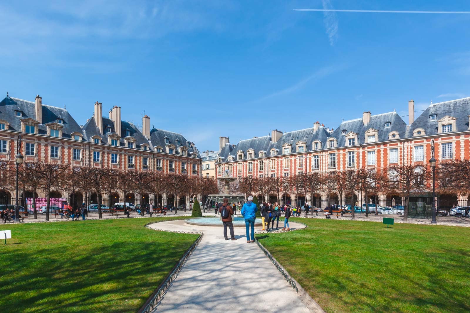 The beautiful arches and manicured lawns of the Place des Vosges square in the Le Marais district of Paris.