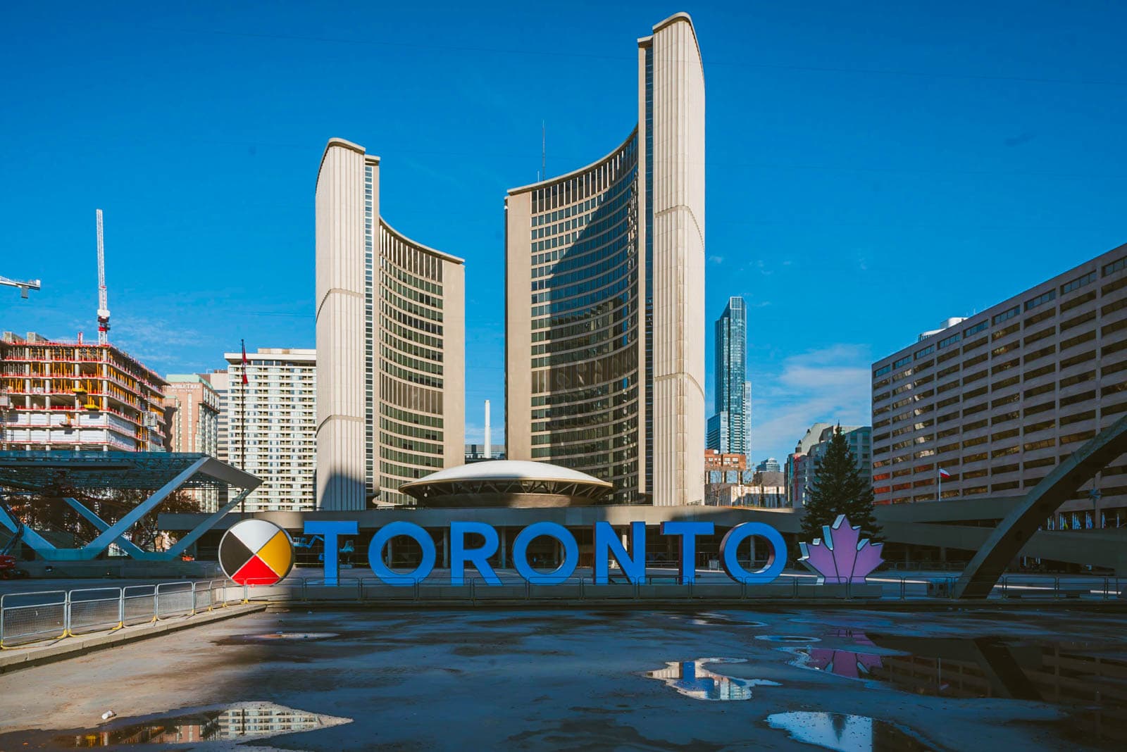 the iconic 3D TORONTO sign at Nathan Phillips Square, with City Hall in the background.