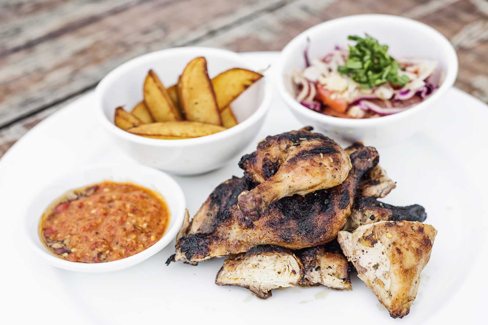 A platter of smoky, charcoal-grilled Piri-Piri chicken, a famous dish from the Algarve region of Portugal.