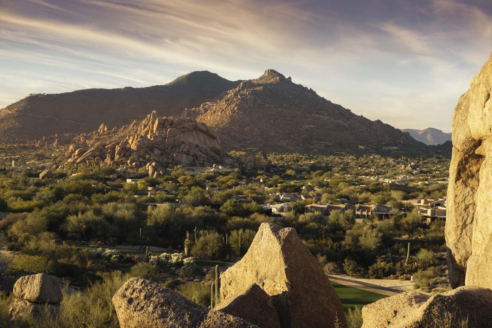 A wide sunset view over the city and desert mountains from a viewpoint in Scottsdale, Arizona.