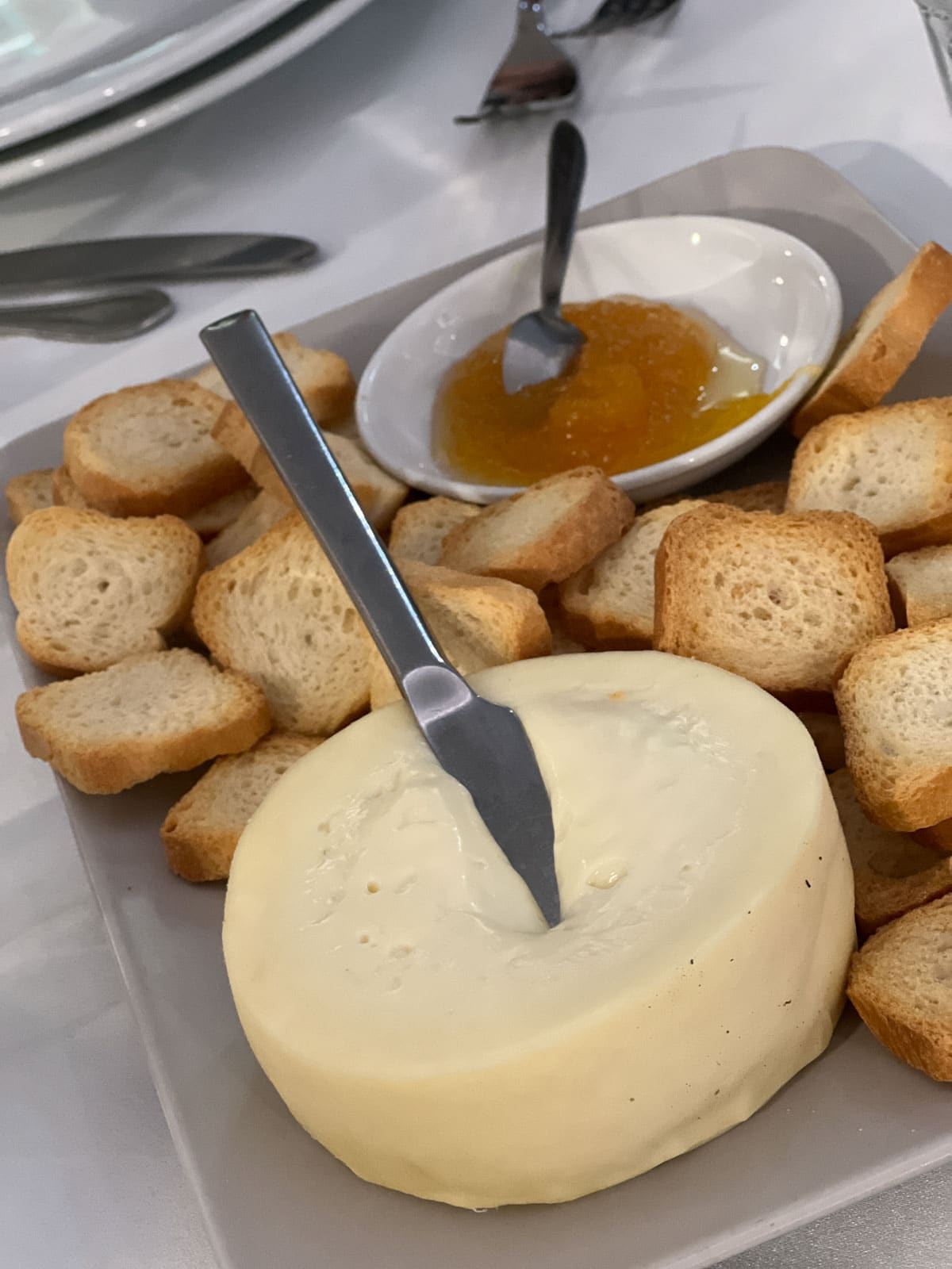 A wheel of soft, gooey Serra da Estrela cheese with the top cut off, ready to be scooped with bread.